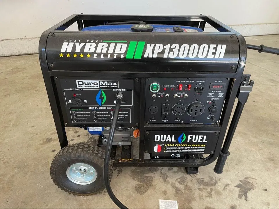 Image of a DuroMax Hybrid Elite XP13000EH generator on a concrete floor. The generator has dual fuel capabilities, with various controls and outlets visible.