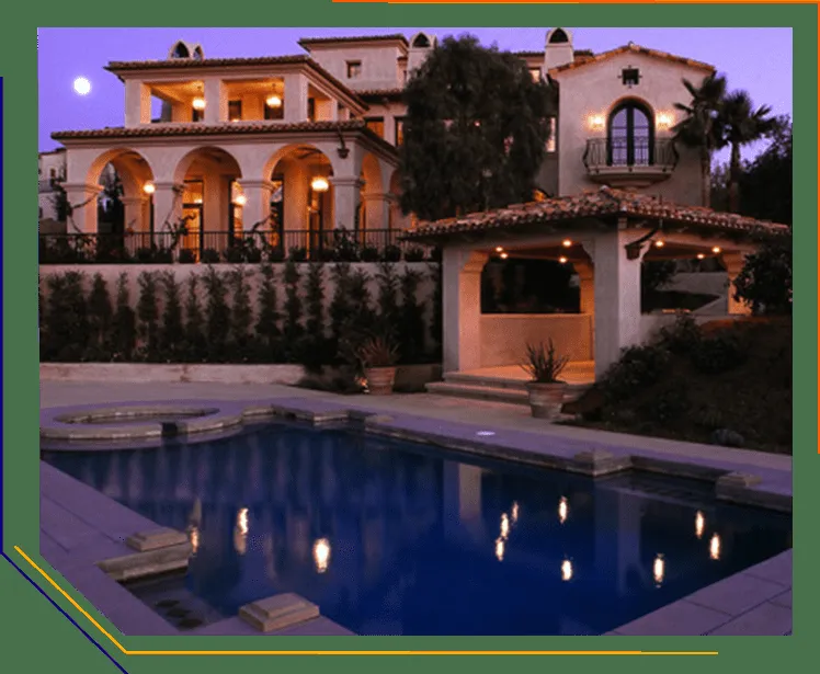 A beautifully lit Mediterranean-style villa with a swimming pool, featuring elegant night lighting, installed by Integrity Electric, Inc. in San Rafael.