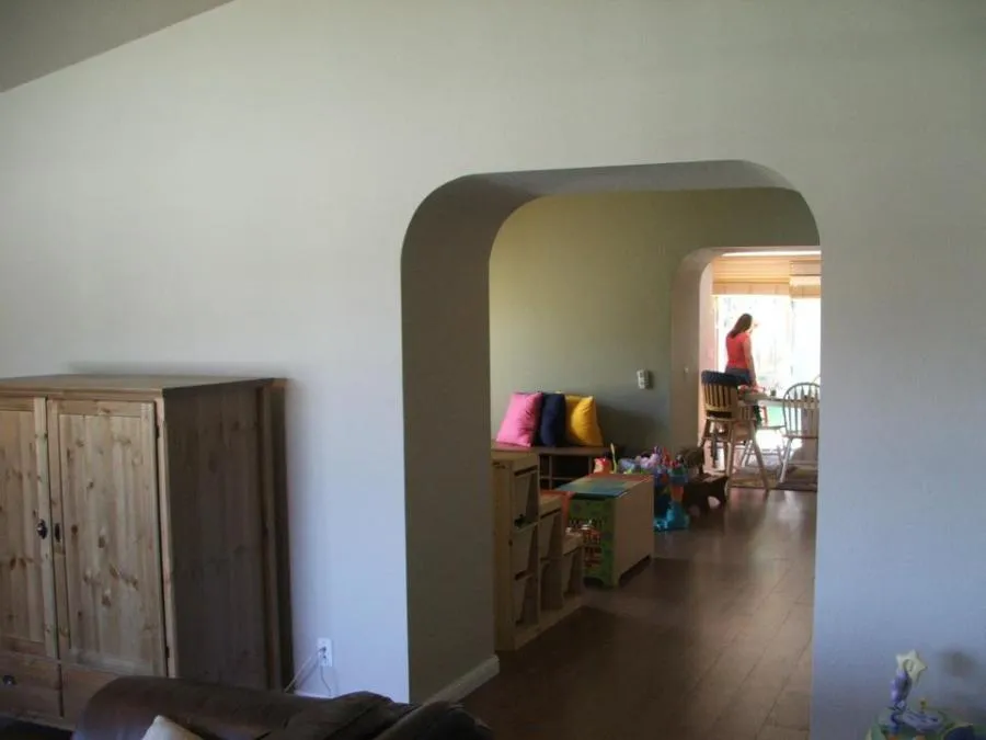 Interior view of a home showing an arched entryway leading to a living area with wooden furniture and colorful cushions, designed by Irwin Construction Kitchen and Bath in Gilroy.