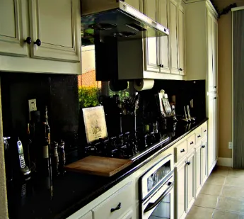 A modern kitchen featuring sleek black countertops, white cabinetry, and stainless steel appliances, designed by Irwin Construction Kitchen and Bath in Gilroy.