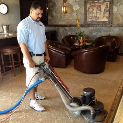 A professional cleaning technician using carpet cleaning equipment in a well-appointed room at JC Carpet & Upholstery Cleaning, Inc. in Vacaville.
