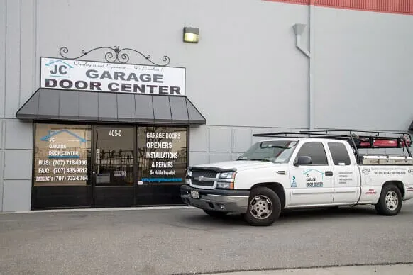 Exterior view of JC Garage Door Center in Suisun City, featuring a company truck parked in front of the storefront with signs for garage door services.