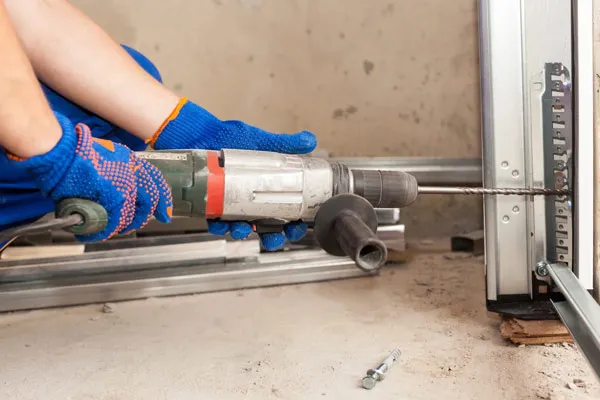 "A person using a drill to install a garage door at JC Garage Door Center in Suisun City, demonstrating careful workmanship."