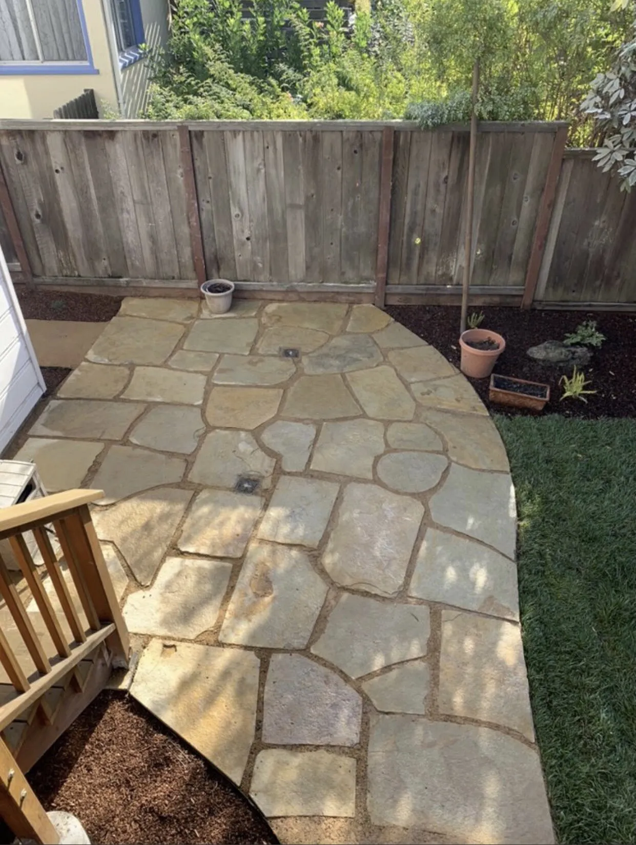 A stone patio and small garden area surrounded by a wooden fence, created by JV Gardening and Landscaping Inc. in Vallejo.
