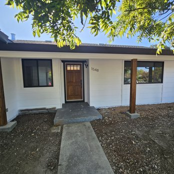 A renovated house exterior with a wooden door and two large windows in Santa Rosa, completed by J A SERRANO CONSTRUCTION.