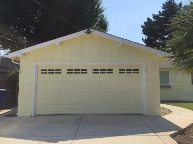 A freshly painted light yellow garage with a white trim, completed by J & J's Final Coat Painting, Inc. in Concord, showcasing a clean and professional finish.