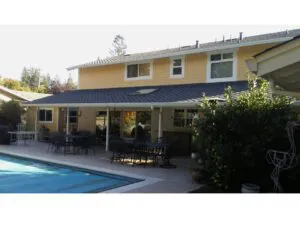 A two-story house with a freshly painted yellow exterior, completed by J & J's Final Coat Painting, Inc., featuring a patio and swimming pool in Concord.