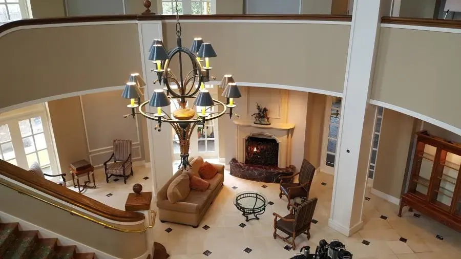 A well-furnished living room with a large chandelier, sofa, armchairs, and a fireplace, showcasing the detailed interior painting work by J & J's Final Coat Painting, Inc. in Concord.