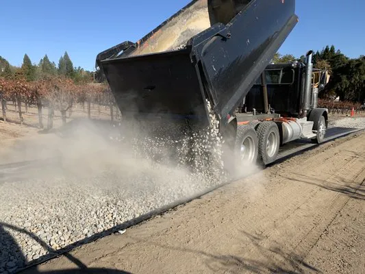 A truck from Jackson's Paving & Equipment Rentals, Inc. spreads gravel on a road in Santa Rosa, illustrating the process of foundational paving work.