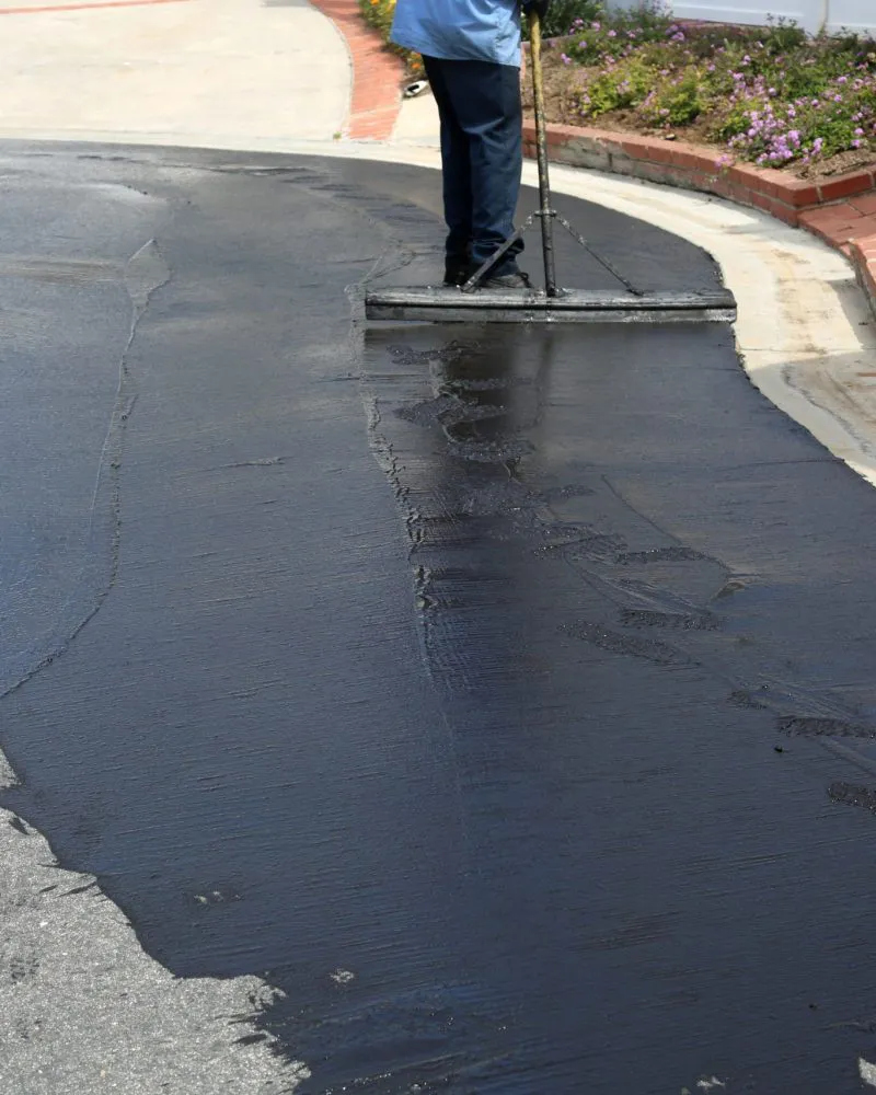 A person spreads asphalt on a driveway, highlighting the paving expertise of Jackson's Paving & Equipment Rentals, Inc. in Santa Rosa.