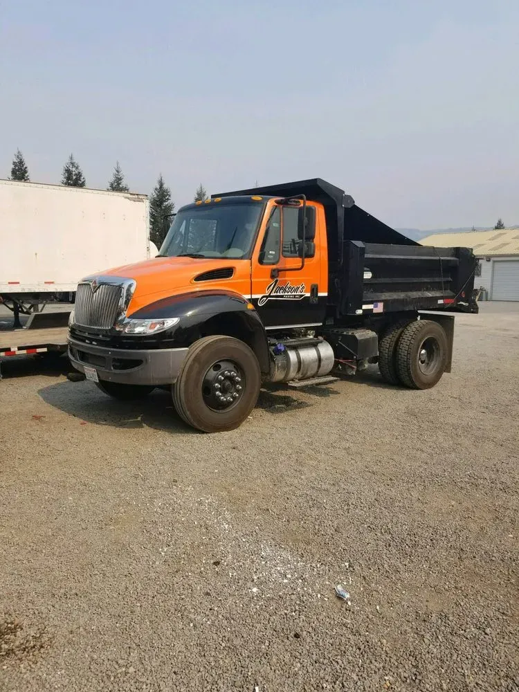 A dump truck from Jackson's Paving & Equipment Rentals, Inc. parked on a gravel lot in Santa Rosa.