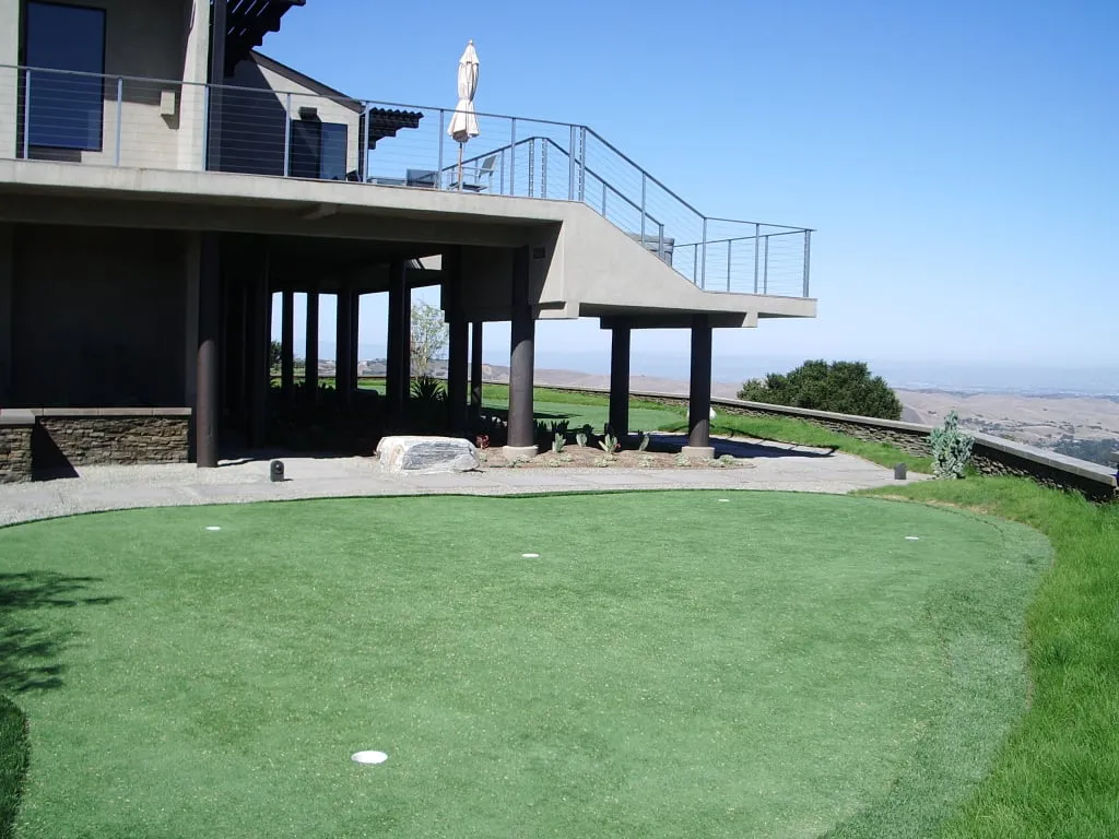 Modern house with an elevated patio and a lush green lawn designed by Jerry Allison Landscaping, Inc. in Watsonville.