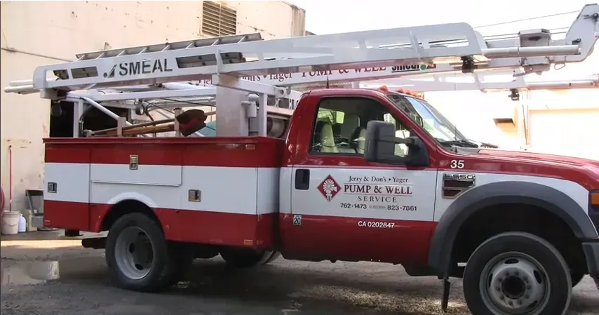 A red and white service truck from Jerry and Don's Yager Pump and Well Service parked in Petaluma, equipped with a large ladder on top.