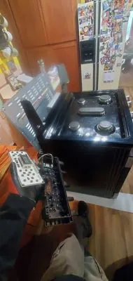 A service technician working on the internal components of a stove with its control panel open, indicating a repair in progress in a kitchen.