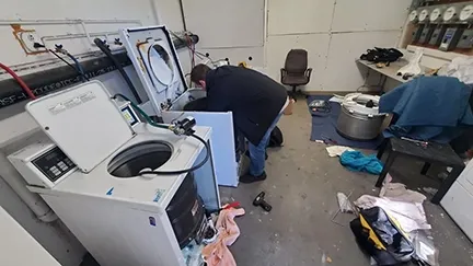 A technician repairing washing machines in a cluttered workshop at Kelly's Appliance Center in Cotati.