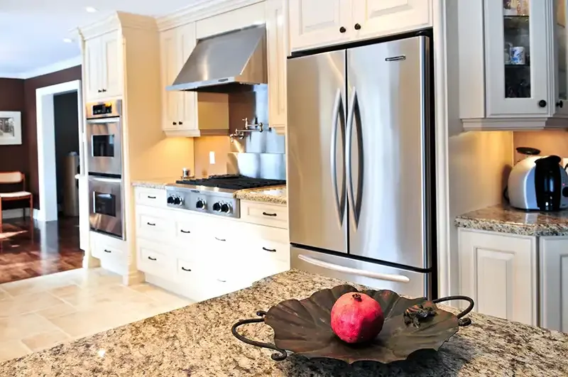 A modern kitchen featuring stainless steel appliances, granite countertops, and a decorative fruit bowl.