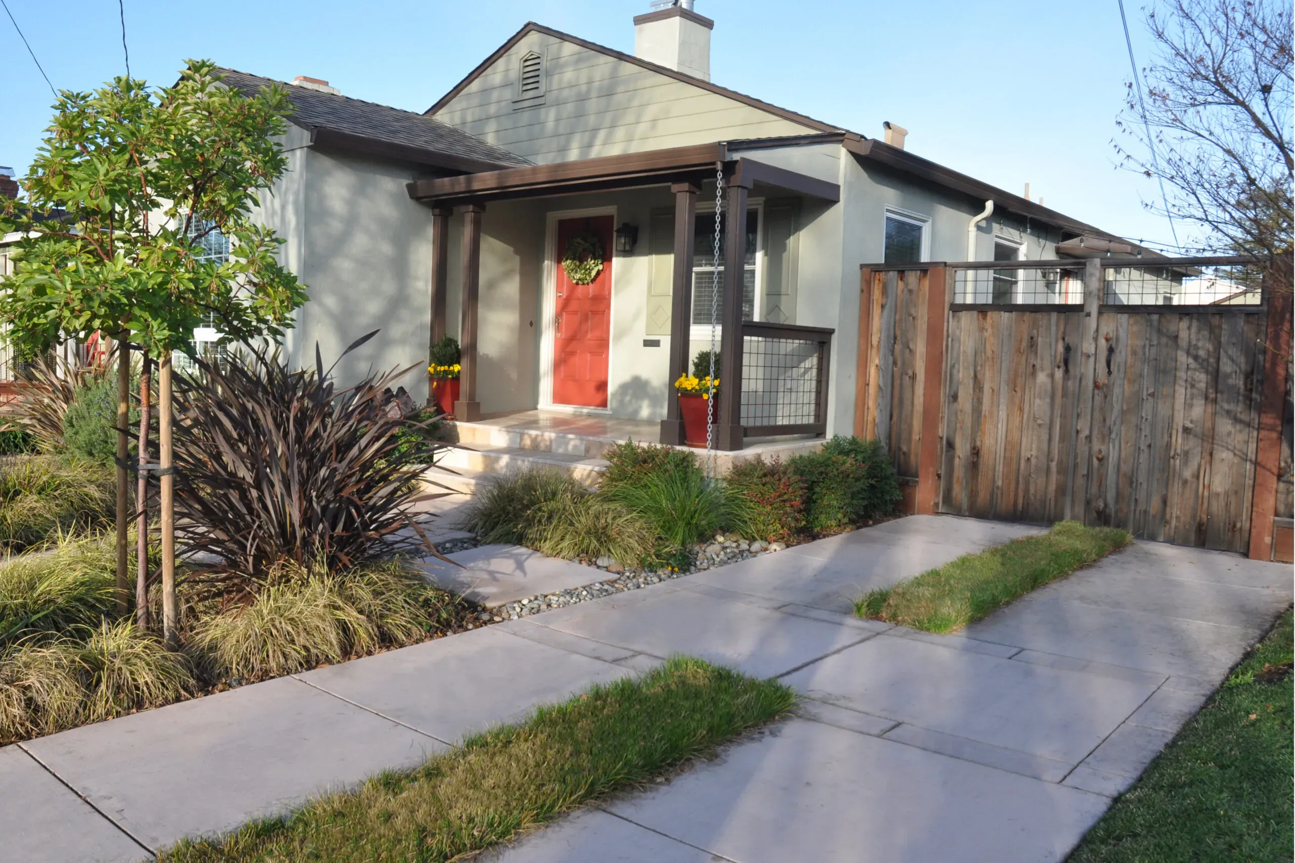 A beige house with a red front door, surrounded by a neatly landscaped garden, showcasing the design work of Koch & Associates, Inc. in Fremont.