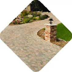 A beautifully paved walkway with adjacent brick column and lantern, surrounded by a landscaped garden area.