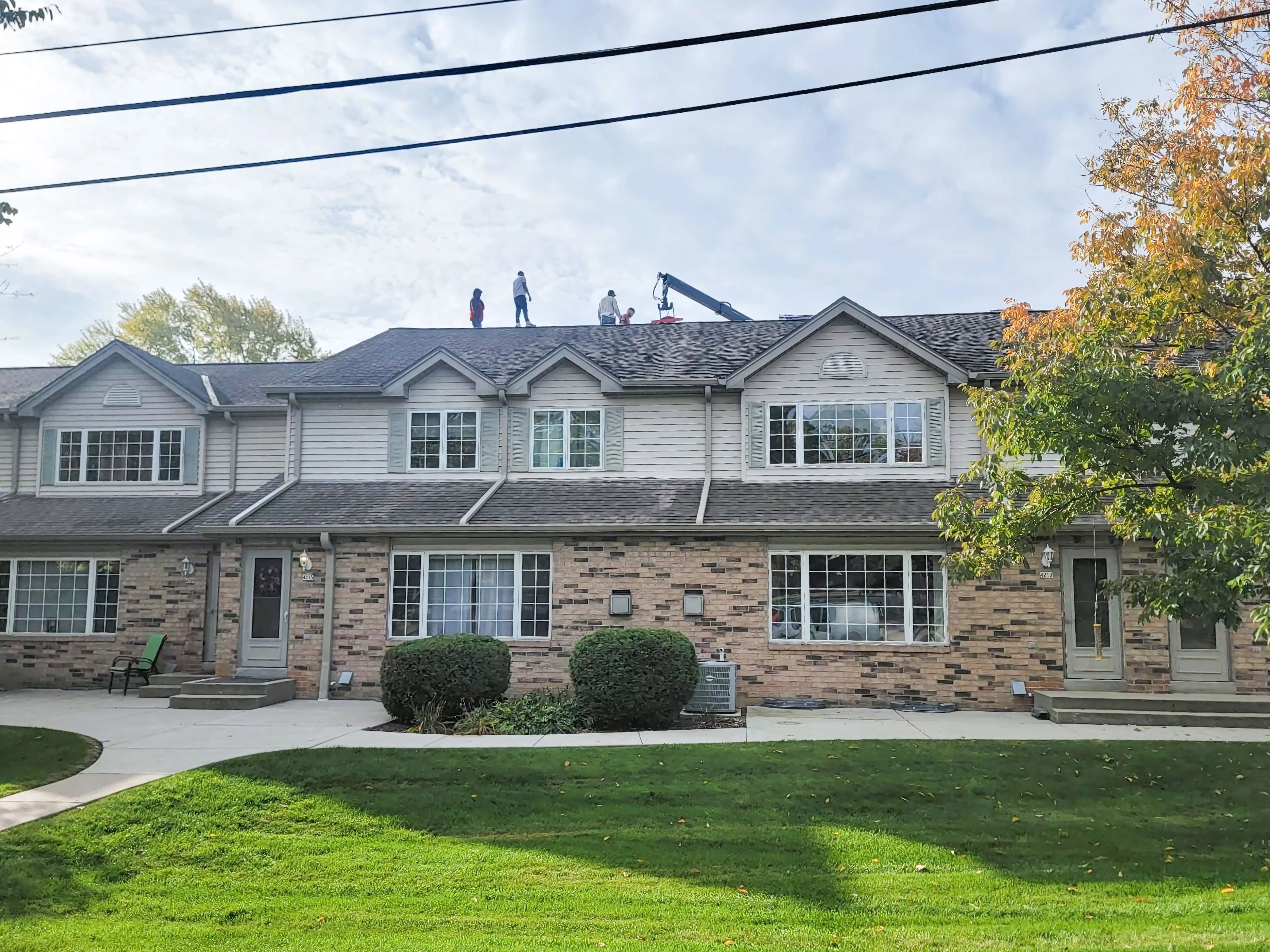Workers from LJ Contractors on the roof of a townhouse, conducting roofing work in Franklin.