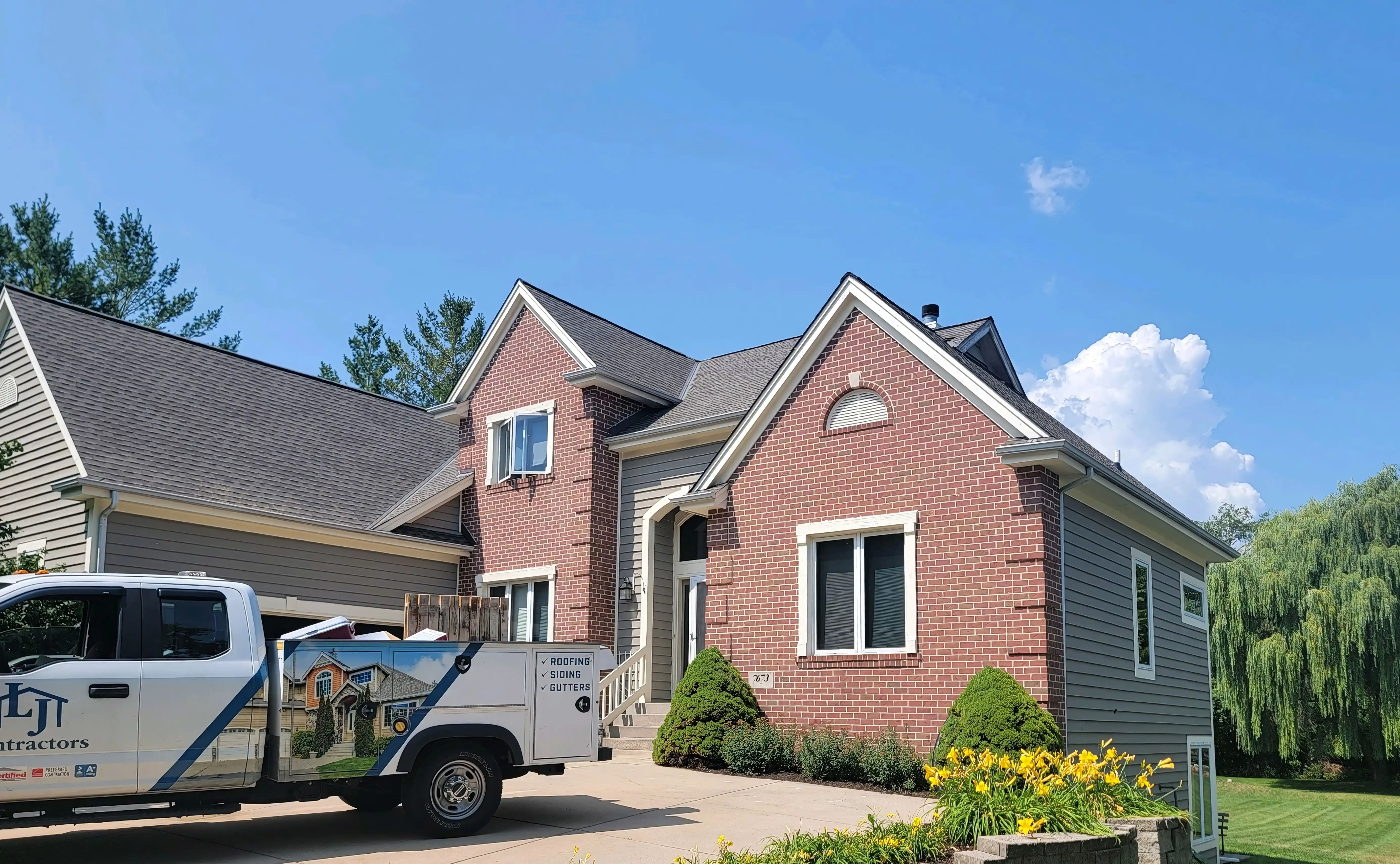 A brick and siding house in Franklin with a truck from LJ Contractors parked in the driveway, featuring clear skies and landscaping.