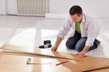 A person installing a wooden floor, with tools like a tape measure and pencil nearby, for LW Construction & Handyman Services in American Canyon.