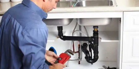 A handyman from LW Construction & Handyman Services working on plumbing under a sink in American Canyon.
