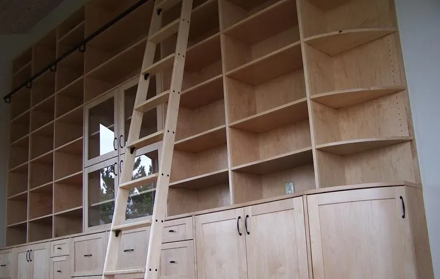 A large wooden shelving unit with multiple shelves and cabinets, featuring a ladder for easy access, built by Labourdette Construction in Sebastopol.