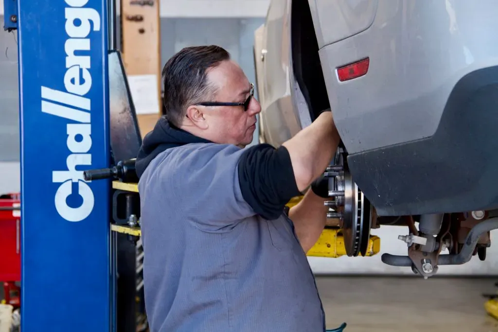 Mechanic working on a car suspended on a lift at Letcher Brothers Auto Repair in Pinole.