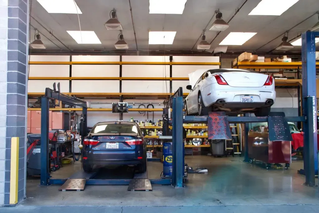 Inside view of Letcher Brothers Auto Repair in Pinole showing cars on hydraulic lifts in a well-equipped service area.