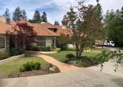A house with a landscaped yard and a Los Gatos Roofing truck in the driveway, located in San Jose.
