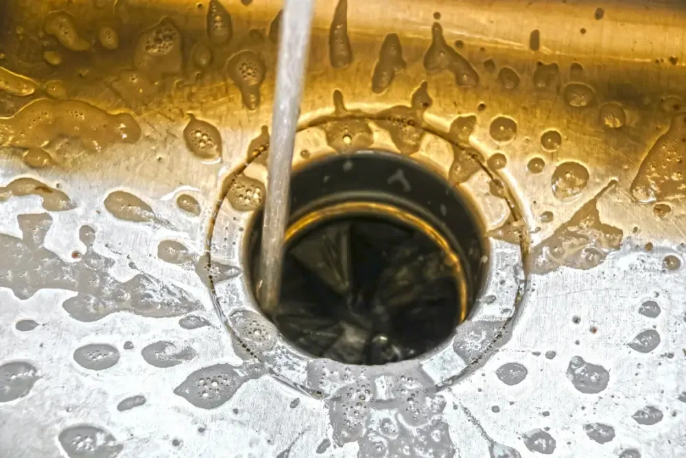 A close-up image of a kitchen sink with water flowing down the drain, emphasizing cleanliness and hygiene.