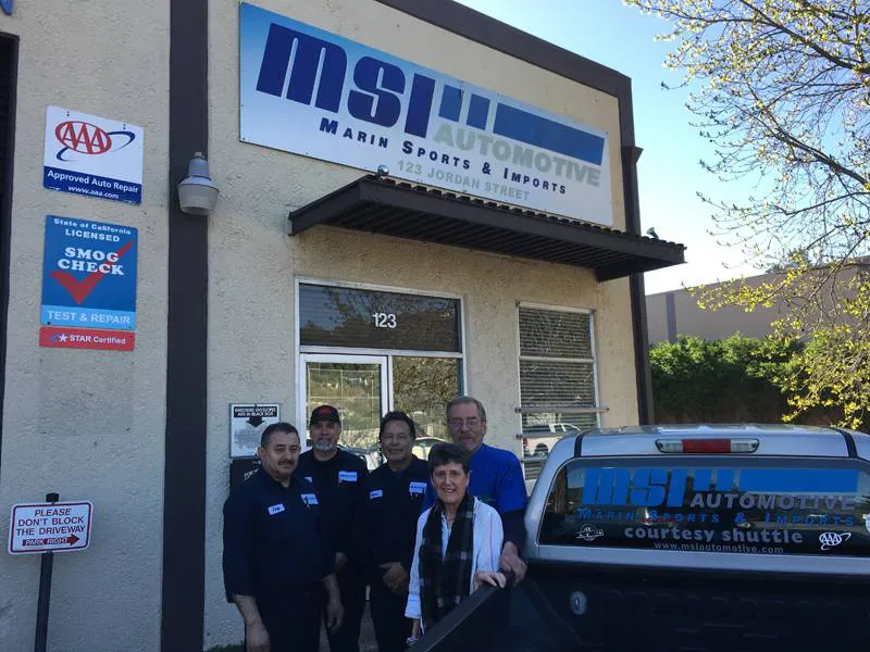 A group of five people standing outside MSI Automotive in San Rafael, with the company sign above and a branded vehicle in front.