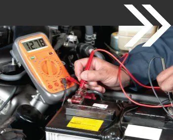 A technician uses a multimeter to test a car battery's voltage at MSI Automotive in San Rafael.