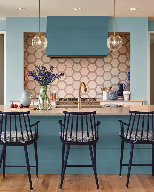 A modern kitchen with a blue island, hexagonal tile backsplash, and stylish lighting, painted by Majestic Painters in Livermore.