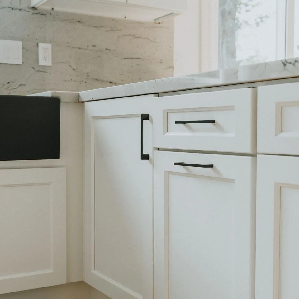 Close-up of white kitchen cabinets with modern black handles, designed by Make It Right Carpentry, Inc in Novato.