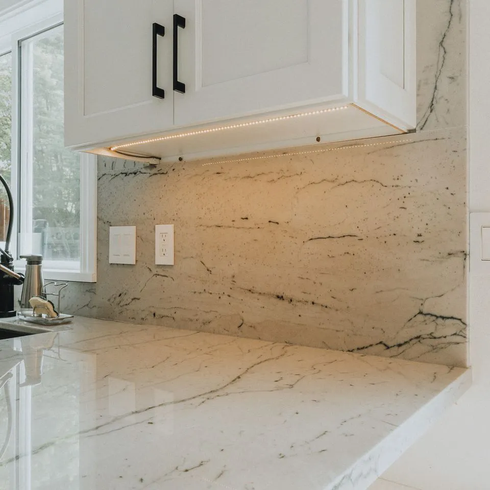 A kitchen countertop with a white marble finish, accented by under-cabinet lighting and a marble backsplash, showcasing the craftsmanship of Make It Right Carpentry, Inc. in Novato.