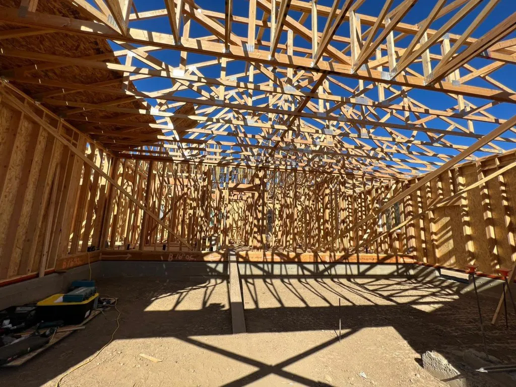 A construction site in Vallejo showing the wooden framework of a building under construction by Mana Construction Inc., with shadows cast by the beams.