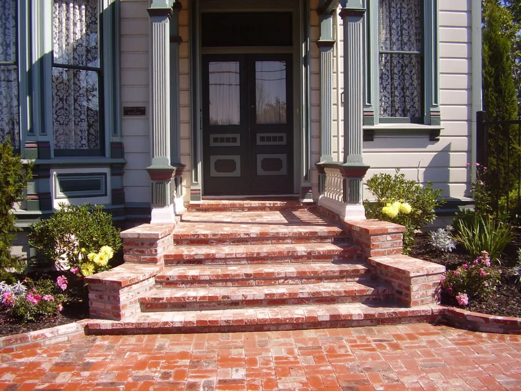 A front entrance with brick steps and walkway adorned with flowers, crafted by Manzanita Landscape Construction, Inc. in Windsor.