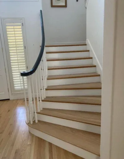 A wooden staircase with a curved handrail, showcasing the craftsmanship of Martinez Stair Co. in Concord.