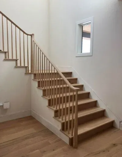 Wooden staircase with light wood finish and vertical railings, designed by Martinez Stair Co. in Concord.