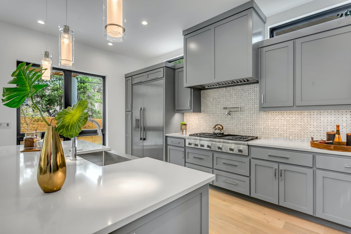 A modern kitchen featuring sleek gray cabinets, stainless steel appliances, and minimalist lighting, crafted by Masterful Construction in San Mateo.
