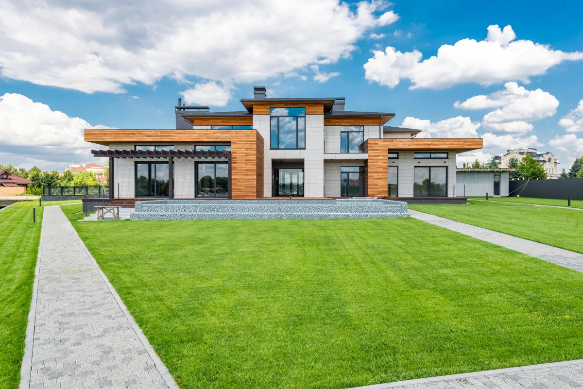 A modern house with wood and glass elements surrounded by a manicured lawn, representing Masterful Construction's project in San Mateo.