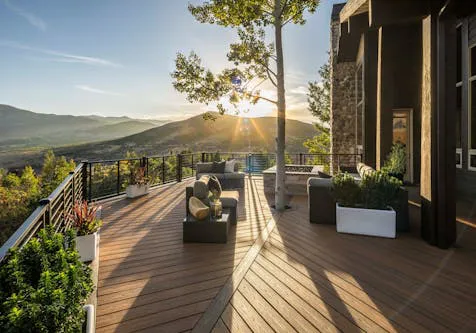 A stunning outdoor deck with modern furniture and panoramic views of a mountain landscape at sunset, constructed by Matthew W. Johnson, General Contractor in Belmont.