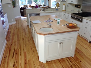 Kitchen with polished hardwood flooring, featuring a central island and white cabinetry, installed by Mattie's Hardwood Flooring in Petaluma.