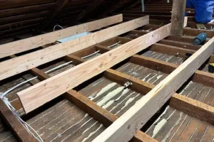 Installation of wooden beams and insulation in an attic space by McHale's Environmental Insulation, Inc. in Concord.
