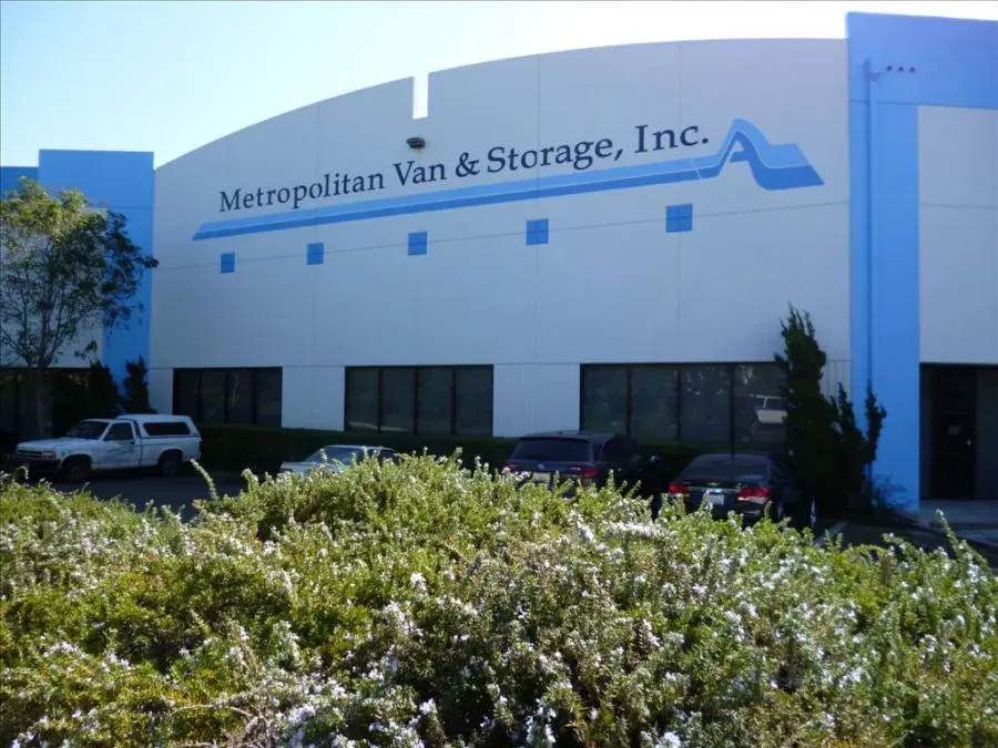 Exterior view of Metropolitan Van & Storage, Inc. building in Fairfield, featuring parked vehicles and surrounding greenery.