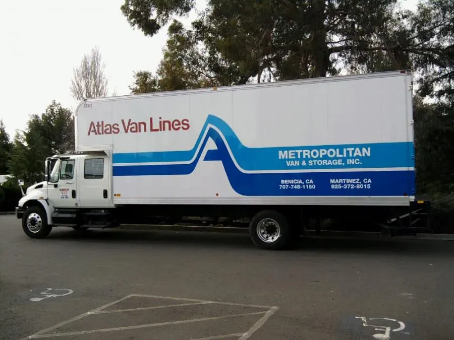A Metropolitan Van & Storage, Inc. moving truck parked in a lot, featuring the company logo and contact information on its side.