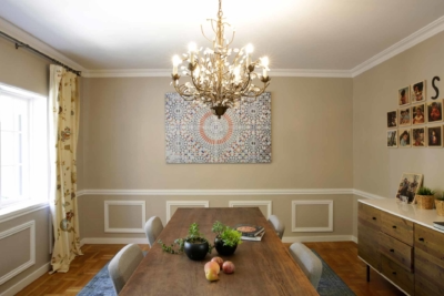 A dining room with a large chandelier, wooden table, and floral art on the wall, showcasing the elegant lighting from Micah Electric Co. in Oakland.