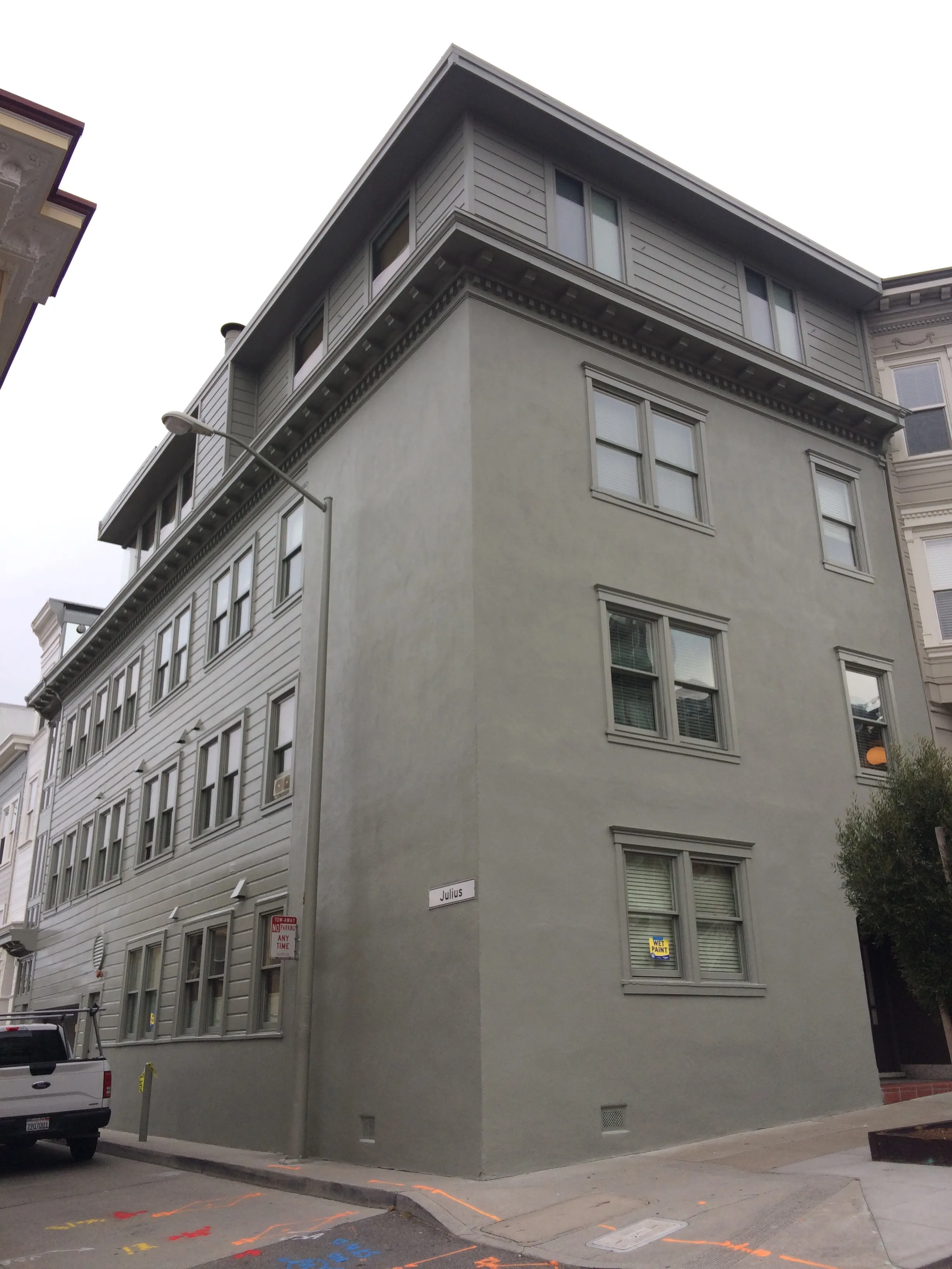 A three-story grey building in San Francisco painted by Michael Sack Painting, Inc., showcasing clean lines and a smooth finish.