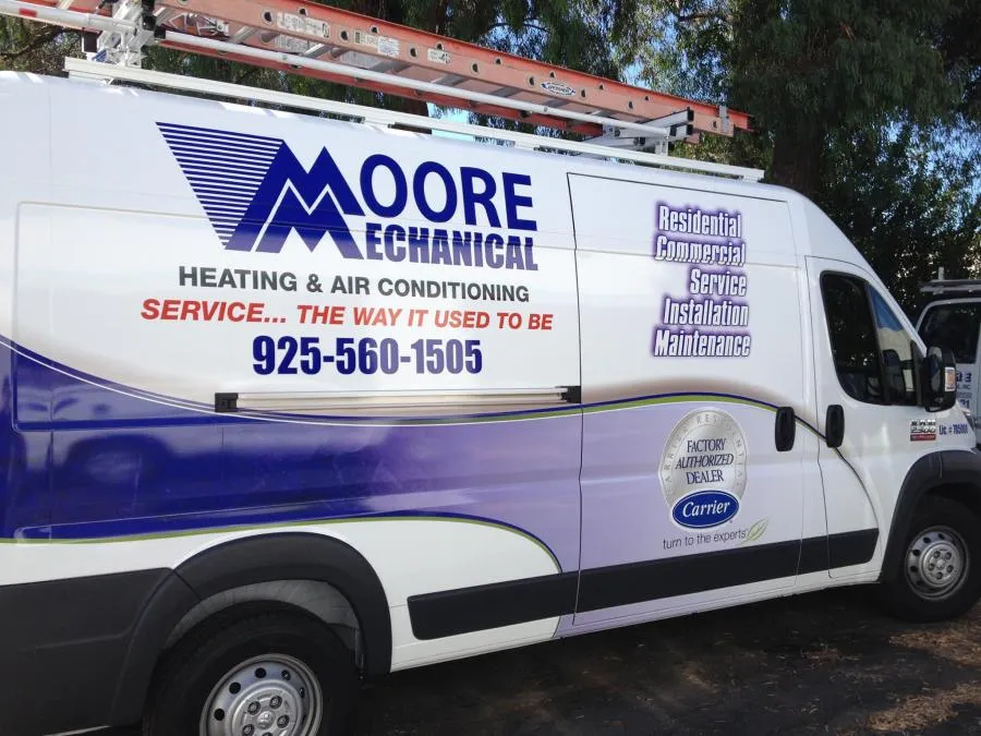 A Moore Mechanical Heating & Air Conditioning service van in Dublin, featuring company branding and contact information.
